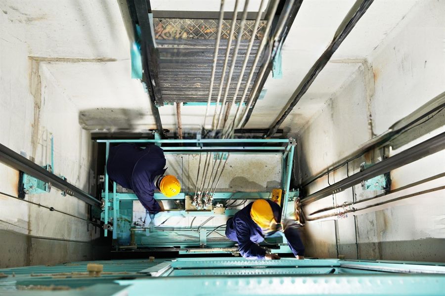 Elevator technicians performing maintenance work inside a lift shaft